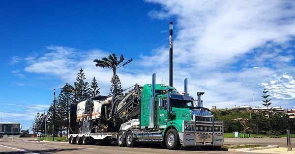 green truck hauling heavy machines