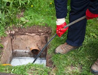 person cleaning outdoor drain