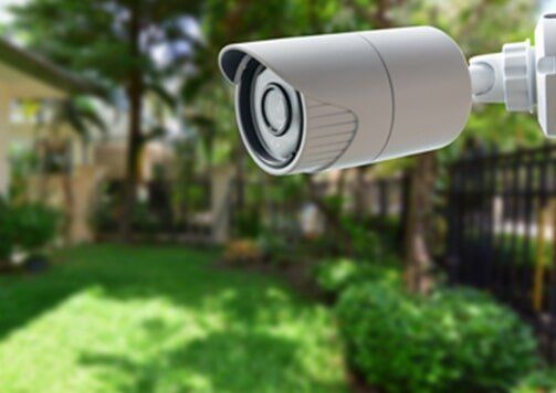 White cctv camera, grass and tress in background — Security Systems  in Tuncurry, NSW
