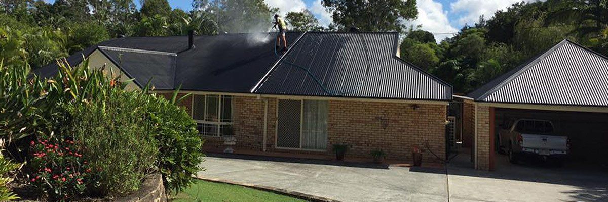 country wide roofing pty ltd worker cleaning old black tiles with water