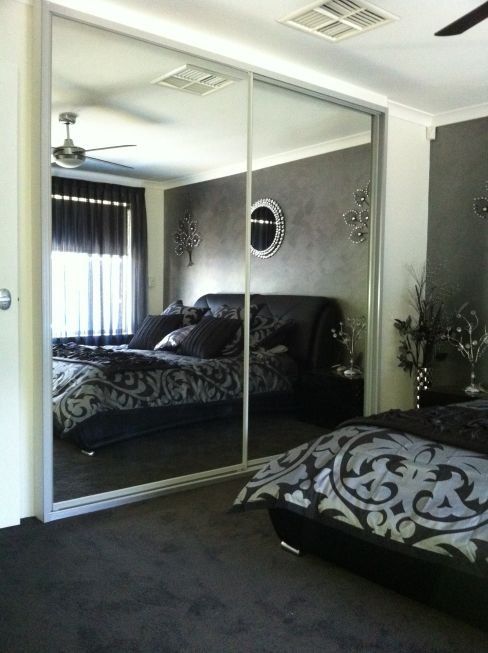 build in wardrobe with sliding mirrored doors and dark brown bed reflection