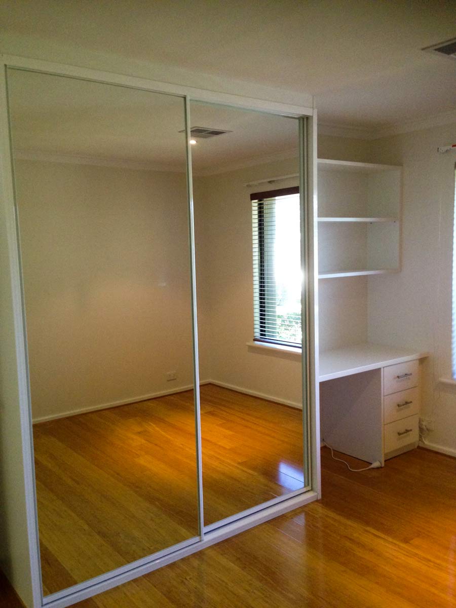 mirrored sliding wardrobe and white desk to the right