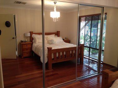 4 door sliding mirrored wardrobe with silver frame reflecting bed