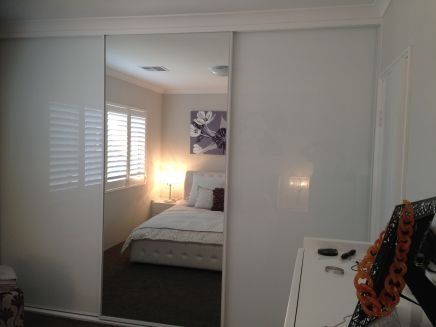 sliding mirrored wardrobe reflecting white bed