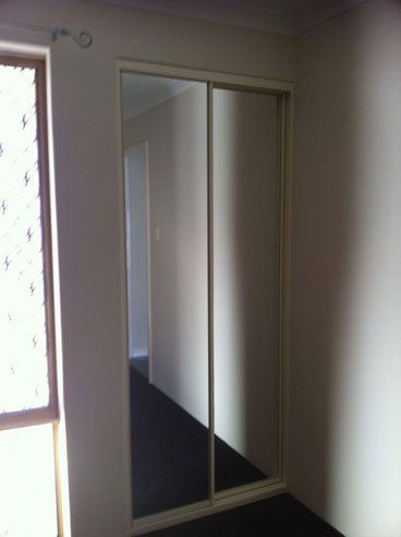 two door sliding mirrored wardrobe in the shadowed corner of room