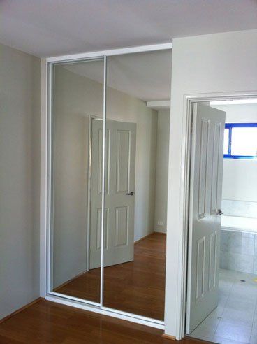 built in mirrored sliding door with white frames next to bathroom door