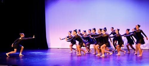 dancers on stage in dark costumes