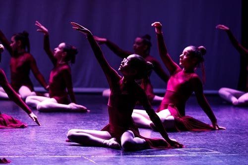 dancers in red dresses on dark stage