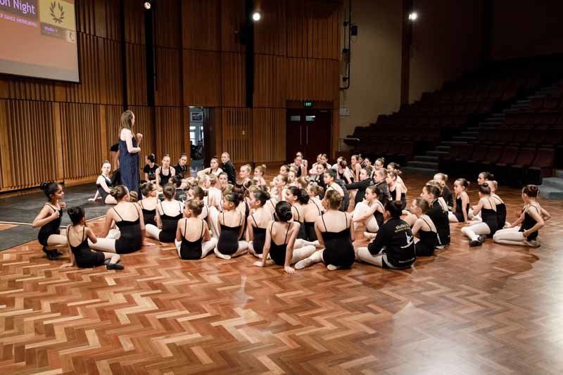 large group of dancers sitting on floor