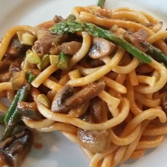 un piatto di spaghetti con sugo di funghi e asparagi