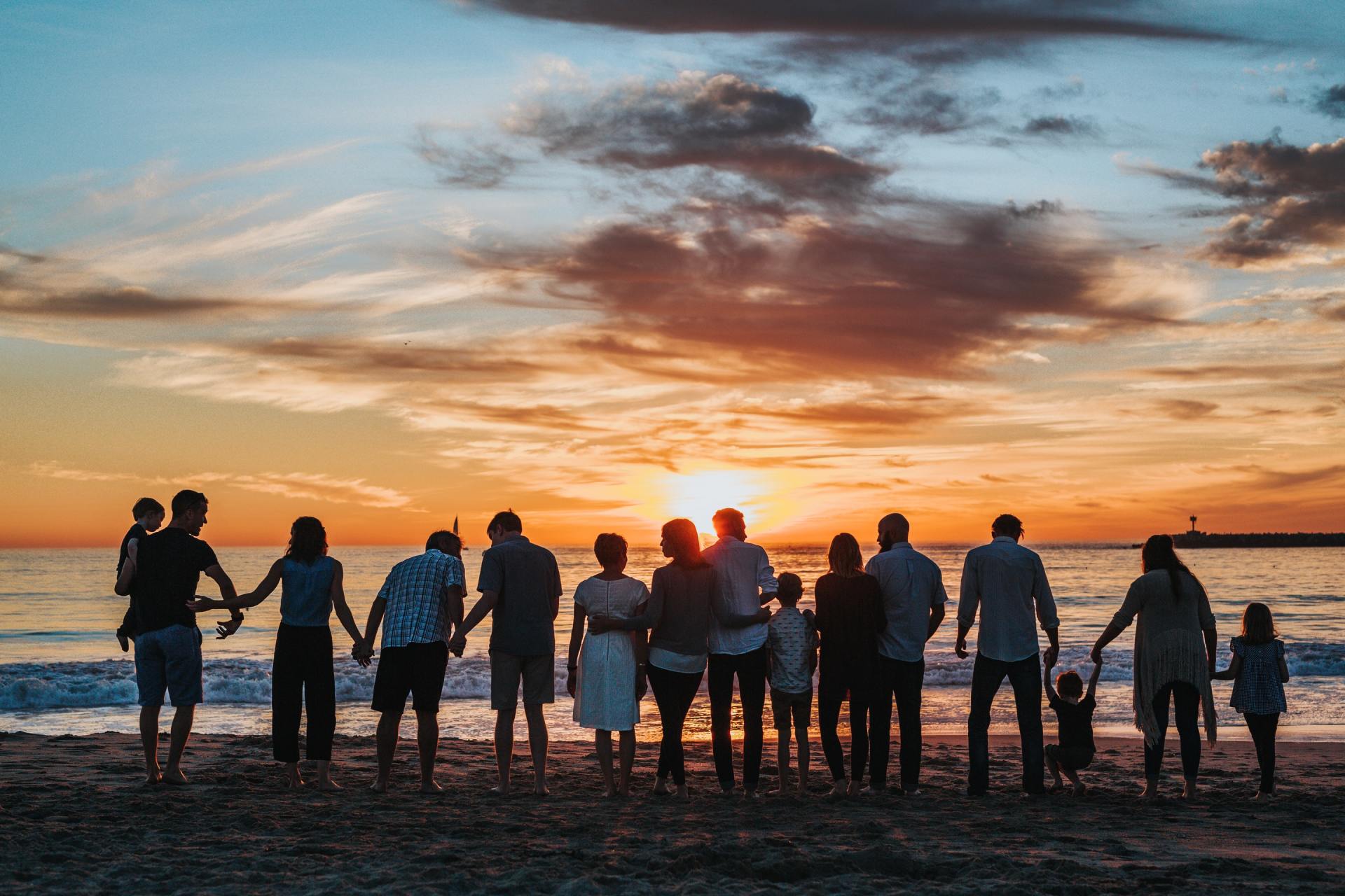 A group of people standing on a beach holding hands